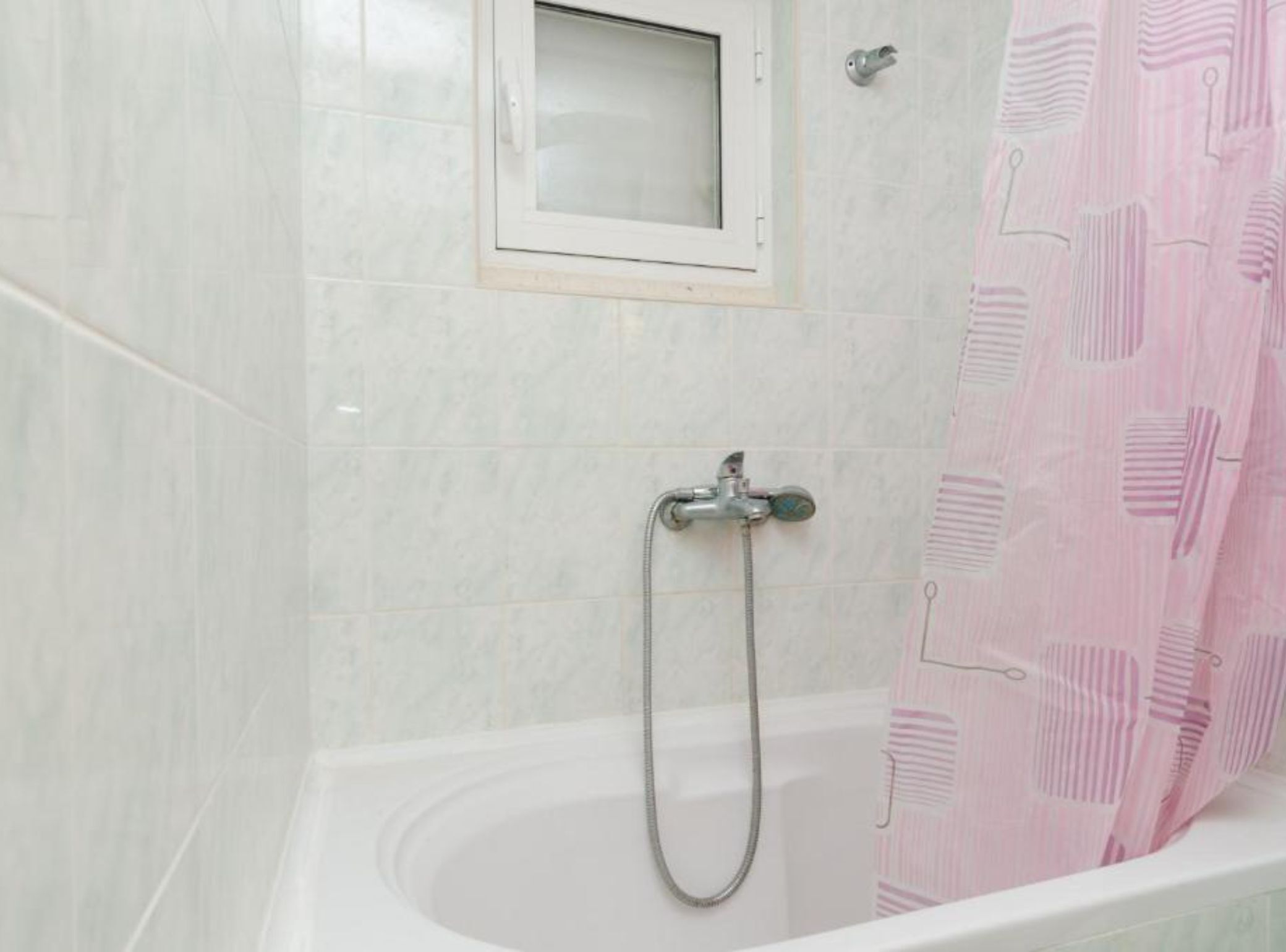 Baño con ducha, ventana y cortina de ducha rosa.