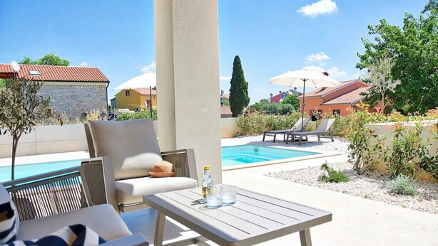 A poolside area with outdoor seating, a pool, and surrounding vegetation. - Villa Onda with private pool and BBQ near Rovinj (Rovinjsko Selo)