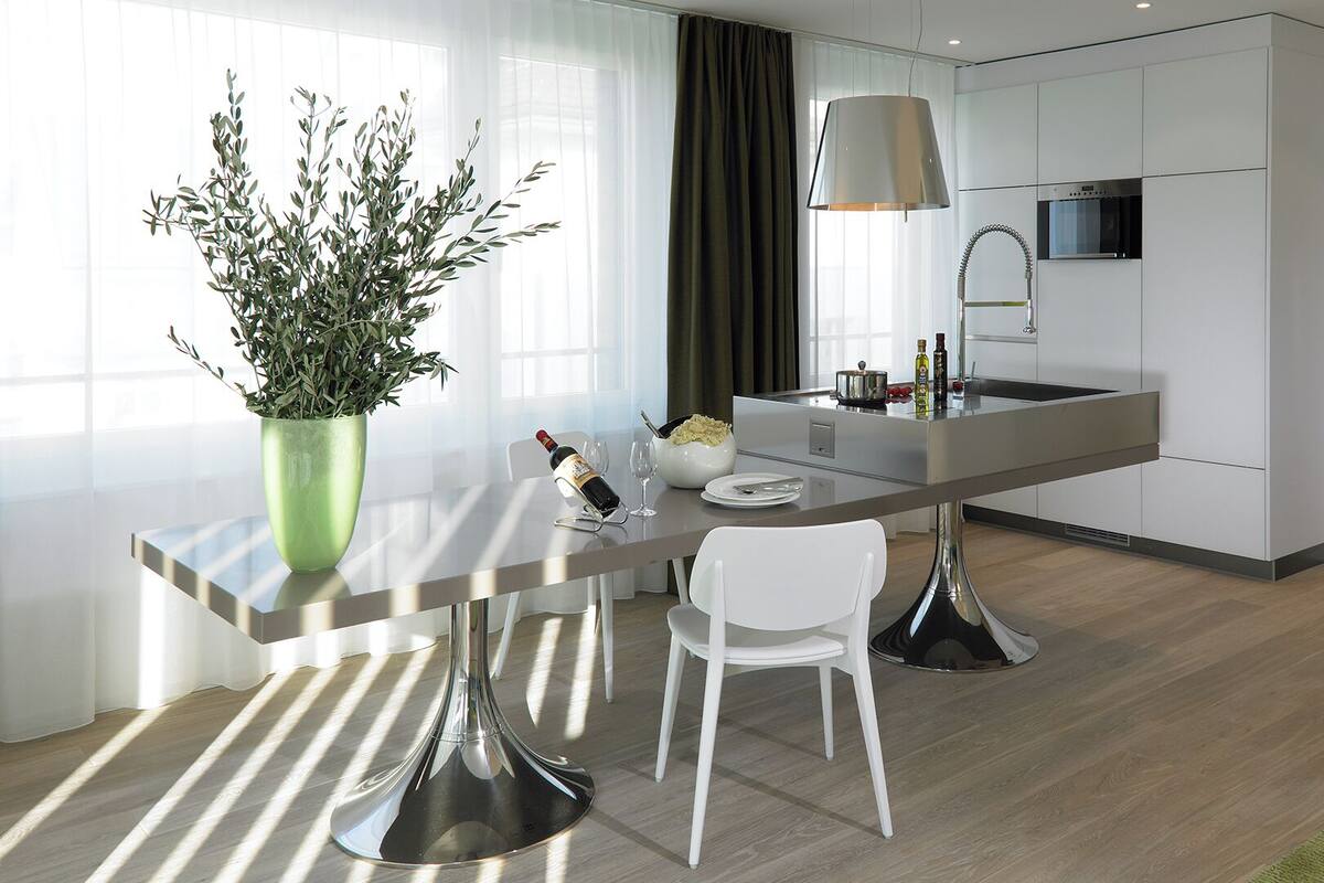 A modern kitchen with a central island, white cabinetry, and a potted plant.