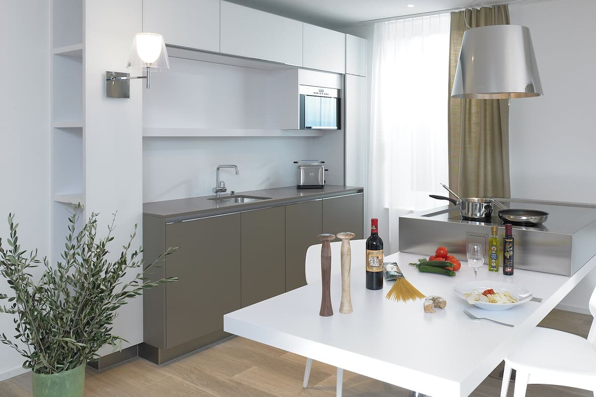 A modern kitchen with a white countertop, stainless steel appliances, and a dining area with a white table and chairs.