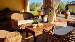 A cozy outdoor seating area with wicker furniture, a wooden table, and potted plants. - Dante Country House - House with Private Pool and Jacuzzi between Florence and Chianti (Toscana)