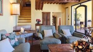 A cozy living room with a wooden staircase, comfortable seating, and a view through a glass door. - Dante Country House - House with Private Pool and Jacuzzi between Florence and Chianti (Toscana)