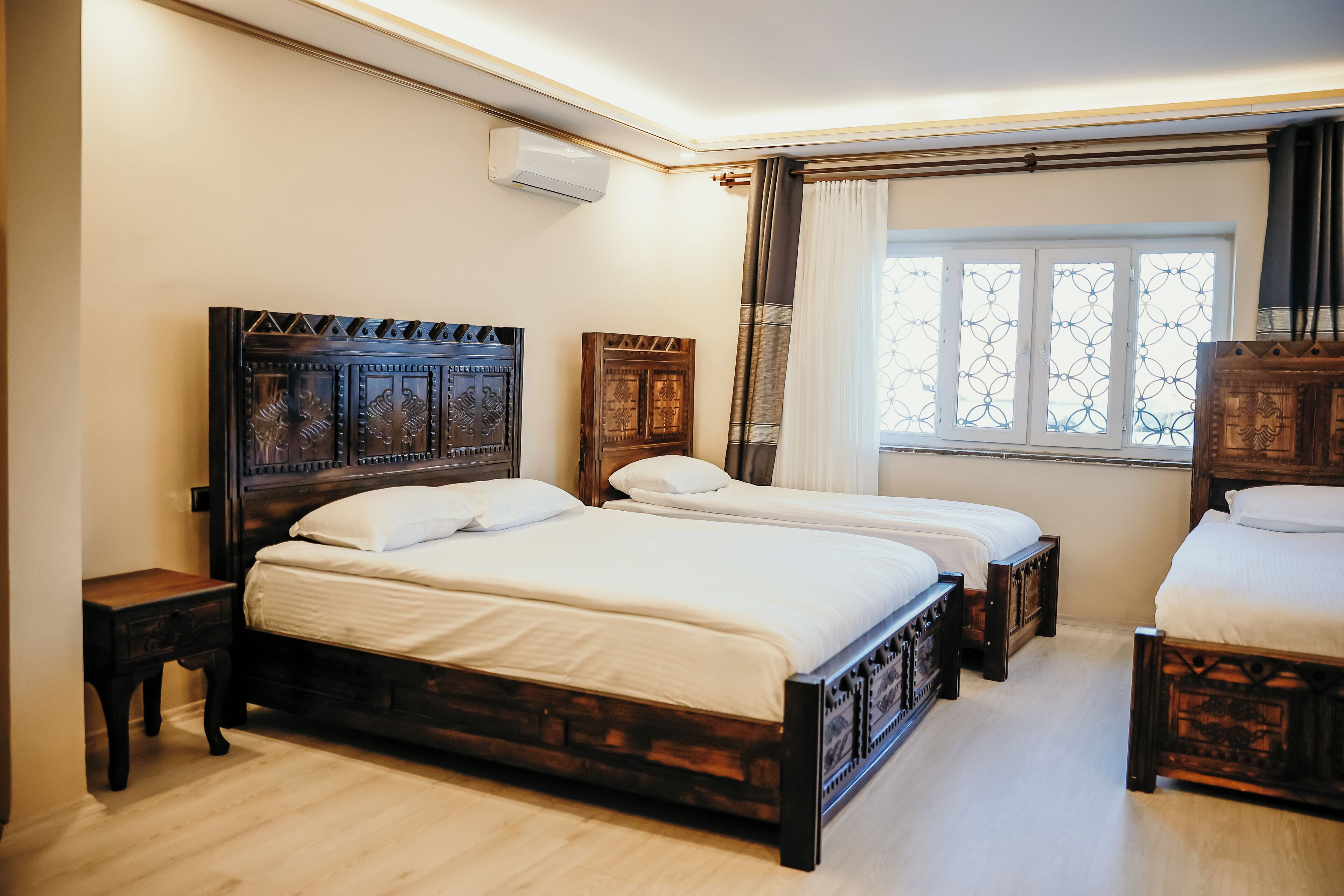 A bedroom with two wooden beds, a nightstand, and a window with curtains.