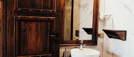 Un bagno con una porta in legno, un lavandino bianco e uno specchio.