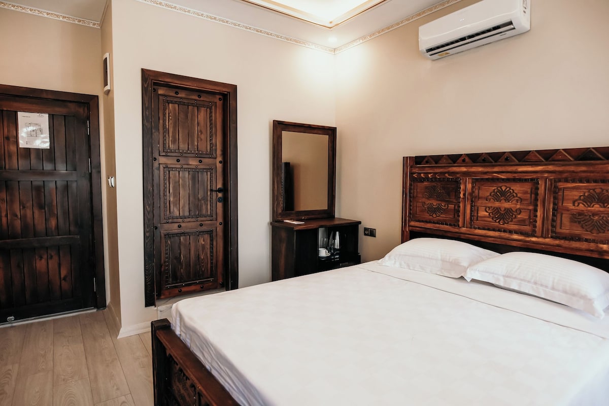 A bedroom with a wooden bed, a nightstand, a mirror, and a wardrobe.