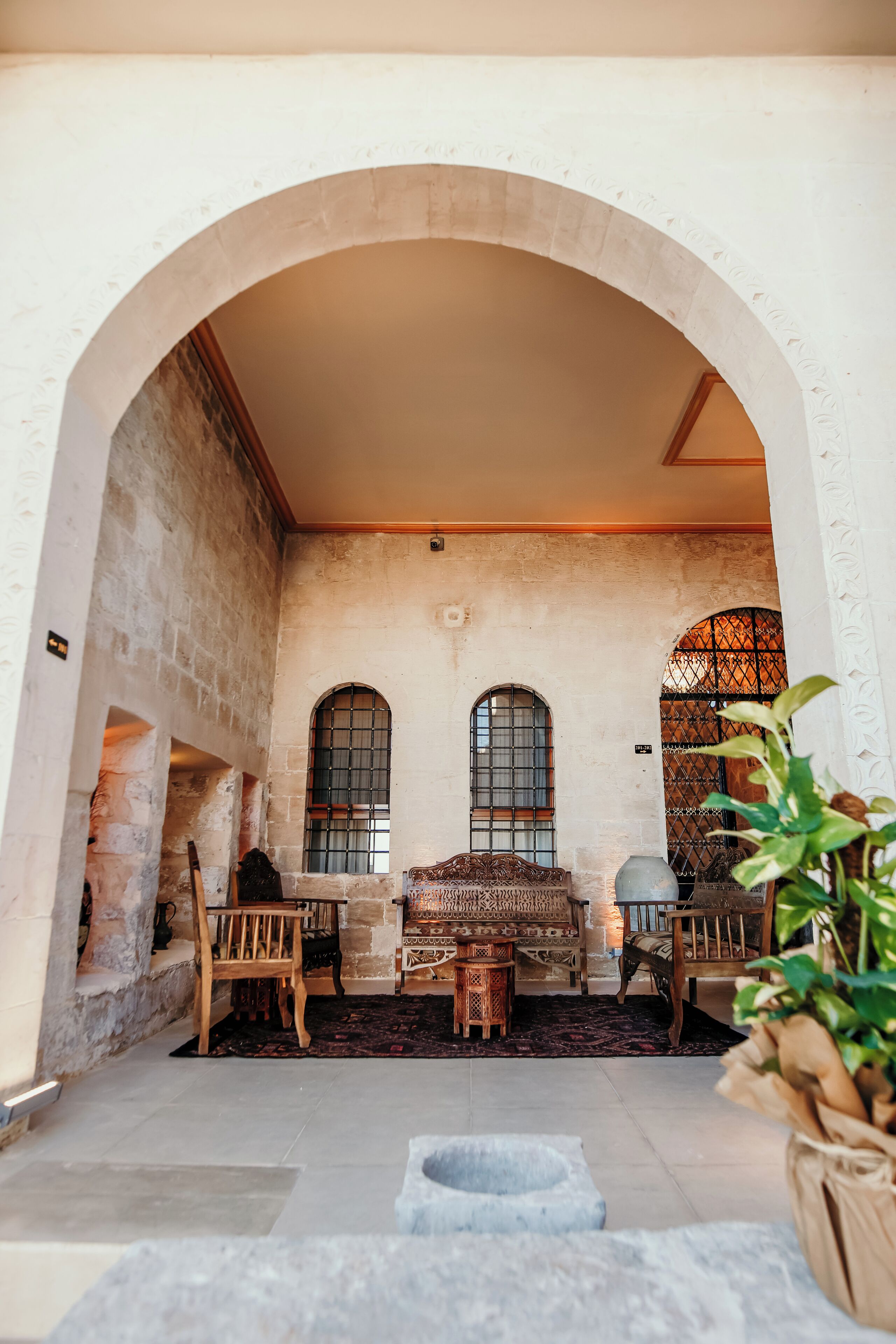 A cozy interior with a stone archway, wooden furniture, and a fireplace.
