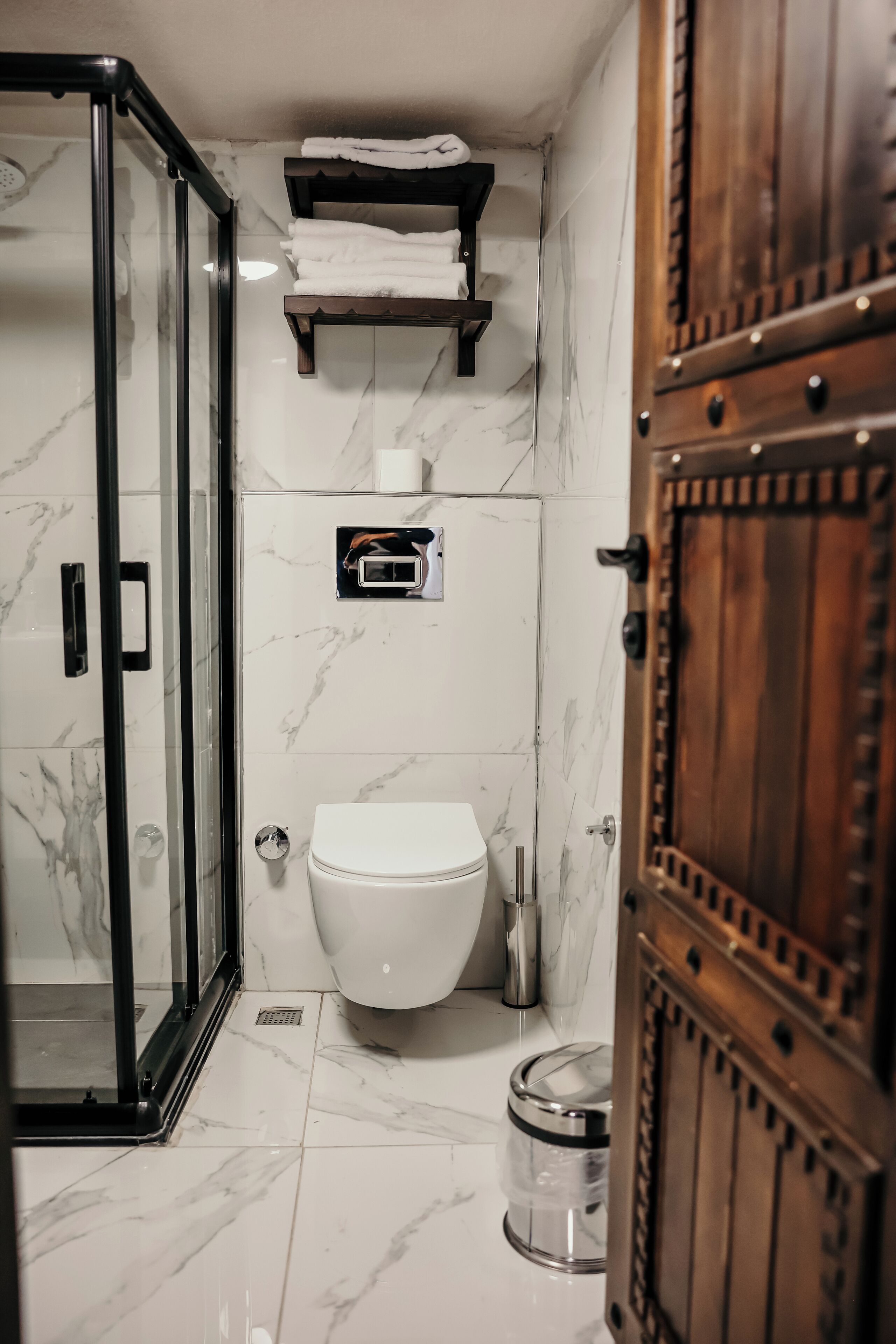 Un baño con cabina de ducha de vidrio, inodoro, lavamanos y un armario de madera.
