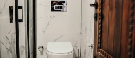 Un baño con cabina de ducha de vidrio, inodoro, lavamanos y un armario de madera.