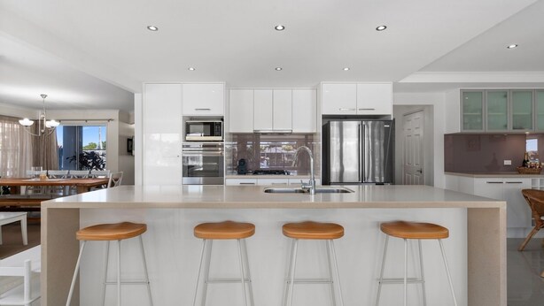 A modern kitchen with a central island, stainless steel appliances, and a dining area with a view.