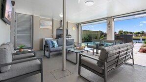 A modern outdoor living space with a pool, grey furniture, and a view of the surrounding area.