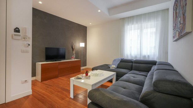 Una sala de estar moderna con un sofá modular, un televisor de pantalla plana y una mesa de centro blanca.