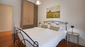 Un dormitorio con cama, armario, un cuadro y mesita de noche.