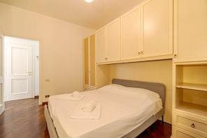 A bedroom with a bed, two white towels, a wardrobe, and a door.