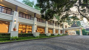 Un hotel con entrada de adoquinado, amplias ventanas y un balcón con barandilla.