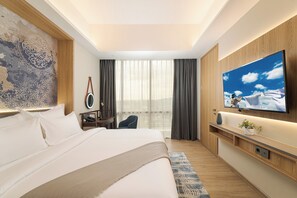 Una habitación de hotel moderna con una cama grande, un televisor de pantalla plana montado en la pared, un escritorio con una silla y un ventanal con cortinas.