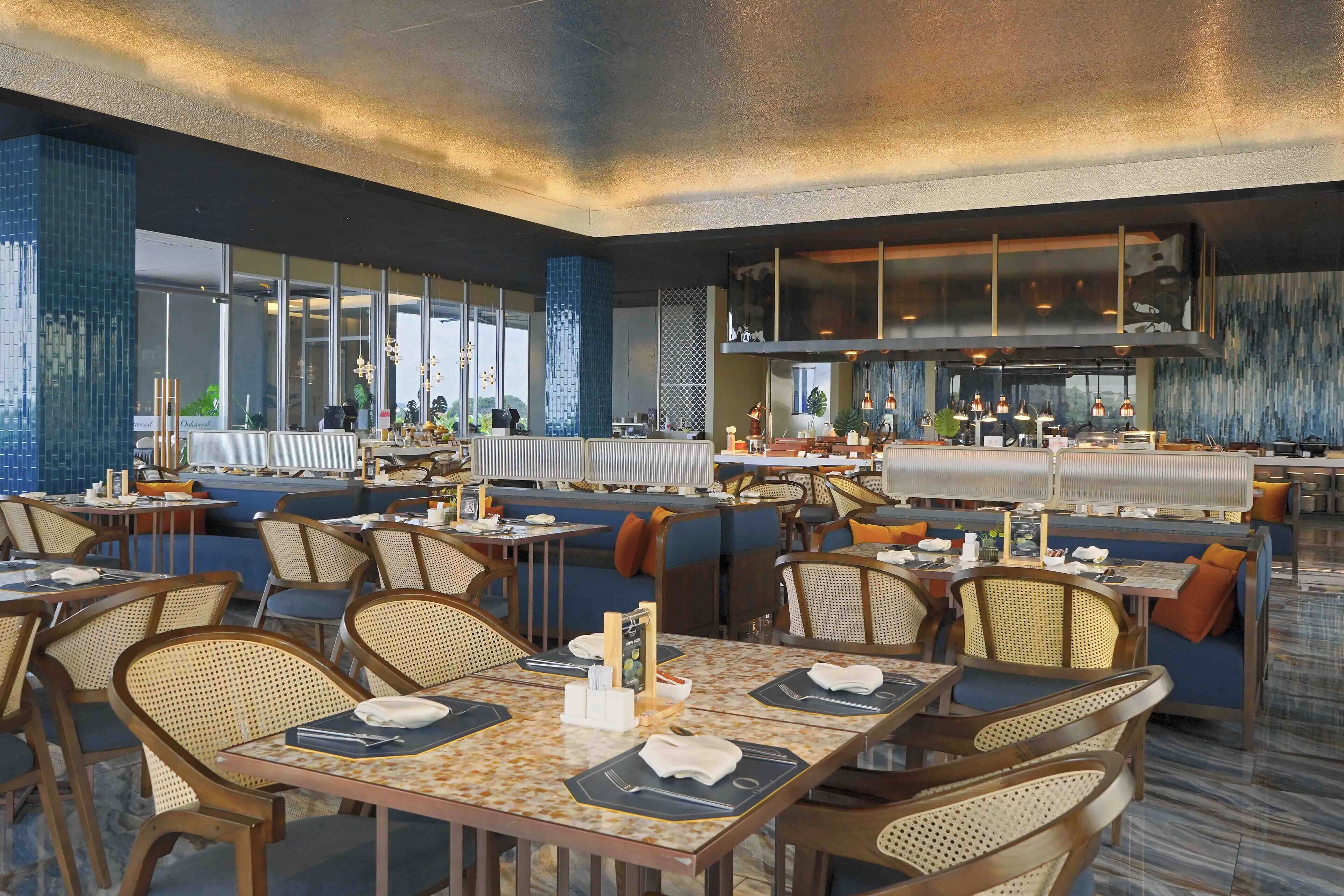 Ein modernes Restaurant mit hohen Decken, großen Fenstern und einer zentralen Bar.