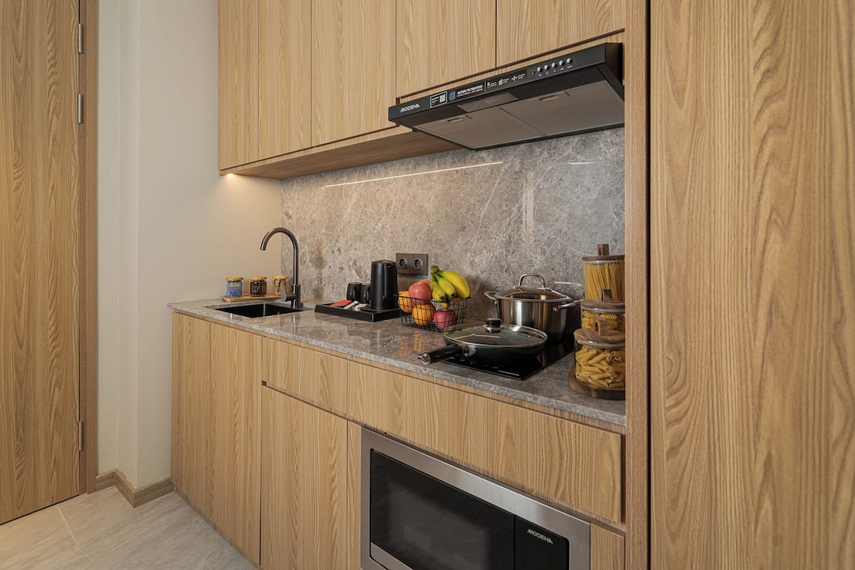 Een moderne keuken met houten kastjes, een inbouwoven en een rvs afzuigkap.