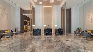 A spacious lobby with marble flooring, three reception desks, and modern lighting fixtures. - Oakwood Hotel & Apartments Grand Batam (Batam)