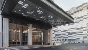 A modern hotel entrance with a covered entrance, large windows, and a parking lot. - Oakwood Hotel & Apartments Grand Batam (Batam)