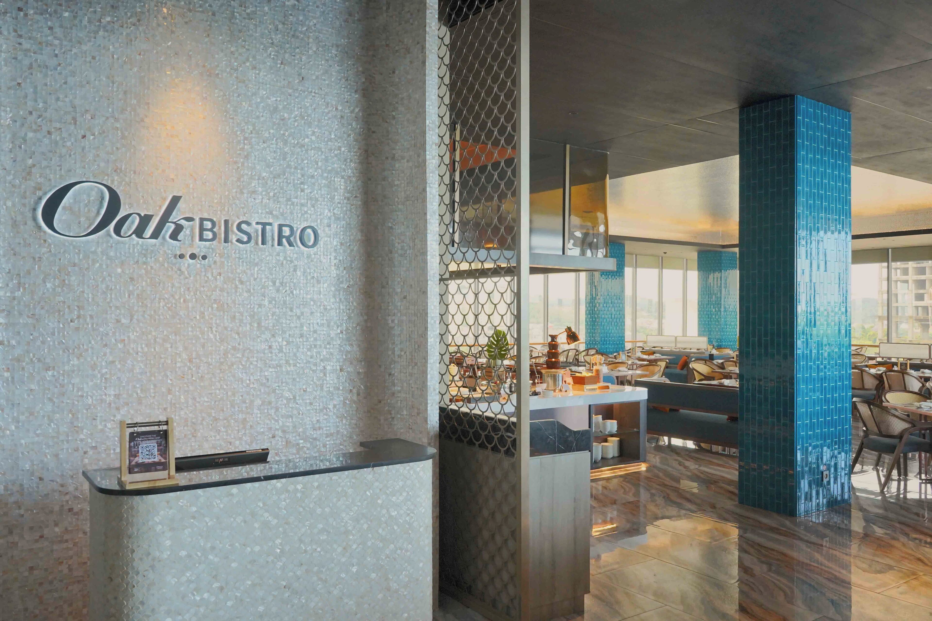 A modern interior of Oak Bistro with a reception desk, seating area, and blue-tiled pillars.