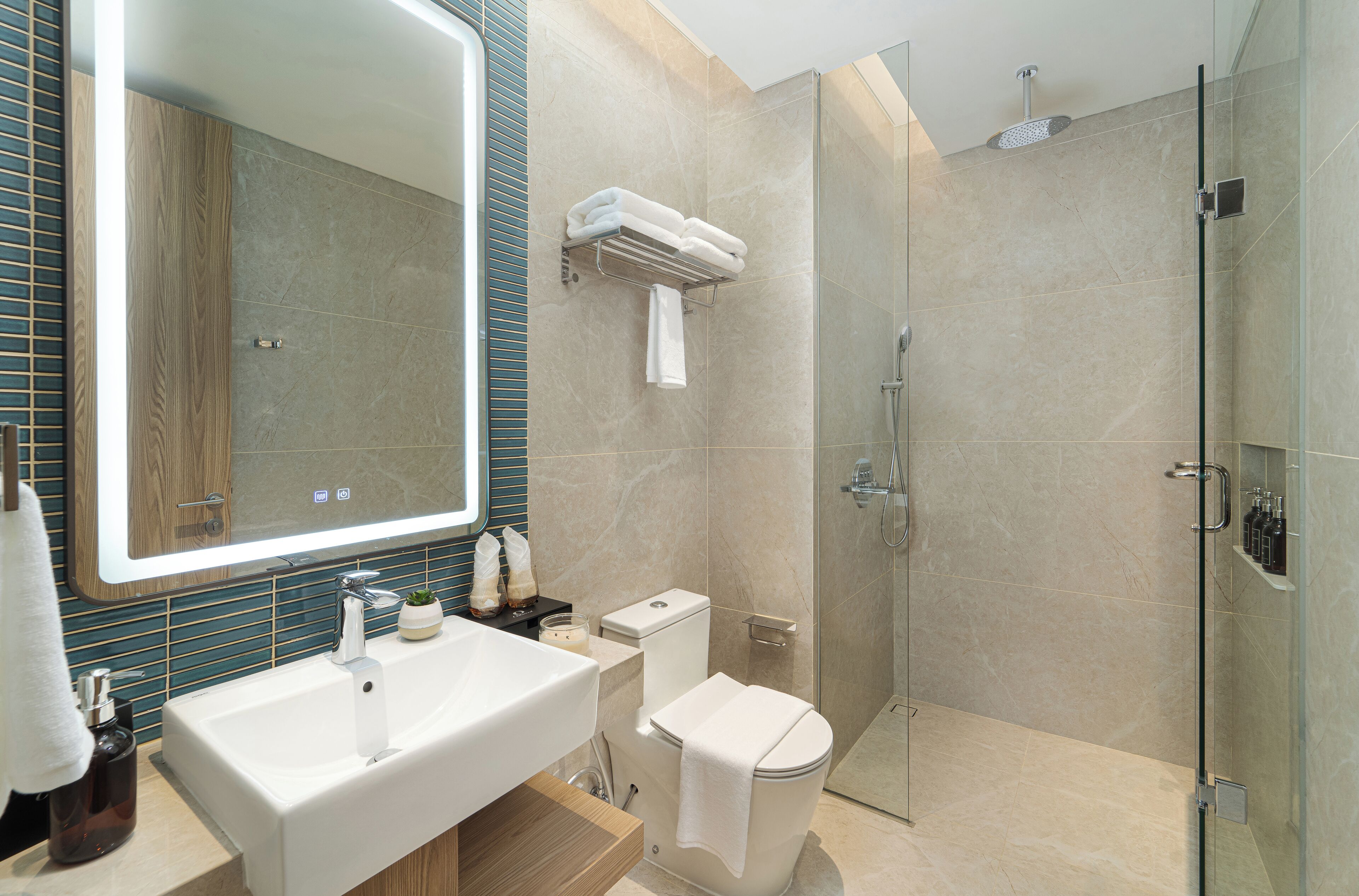 A modern bathroom with a large mirror, a sink, a toilet, and a glass-enclosed shower.