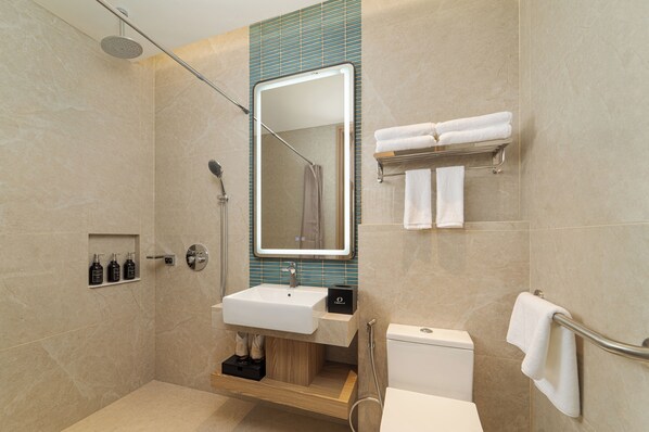 Un baño moderno con lavamanos, espejo, ducha e inodoro.