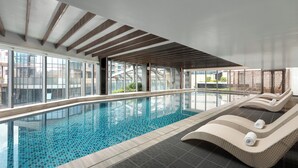 A modern indoor swimming pool with clear glass walls, wooden ceiling beams, and lounge chairs along the poolside. - Fraser Place Wujiaochang Shanghai (Shanghai)