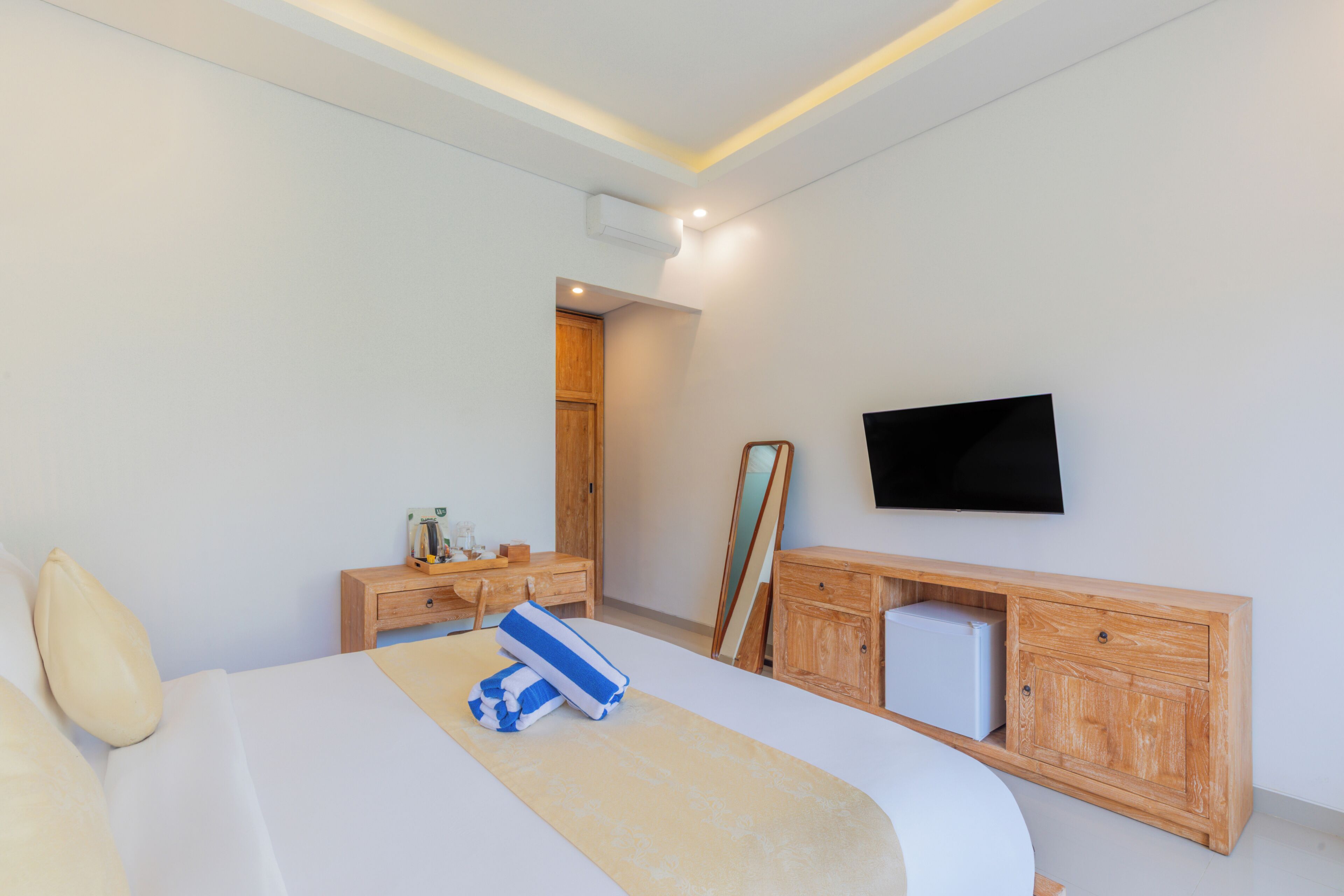 A modern bedroom with a bed, bedside tables, a TV, and a wooden cabinet.