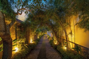 A pathway flanked by bamboo and trees, leading to a building with a tiled roof. - Bali Made Escape (Bangli)