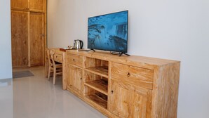 A wooden cabinet with a flat-screen TV displaying a waterfall, a kettle, and a chair. - Bali Made Escape (Bangli)