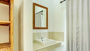 Une salle de bain avec un lavabo blanc, un miroir et un rideau de douche.