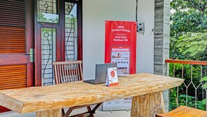 Une table en bois sur laquelle se trouve un ordinateur portable, une banderole rouge et un banc en bois.