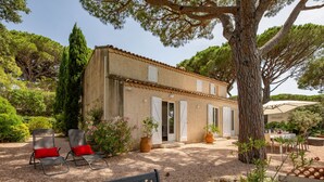 A rustic building with a tiled roof, a gravel patio, outdoor seating, and a large tree providing shade. - Riviera by Interhome (Sainte Maxime)