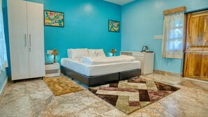 A bedroom with a bed, nightstands, a wardrobe, and artwork on the walls. - Michael's Island Resort (Brahmagiri)