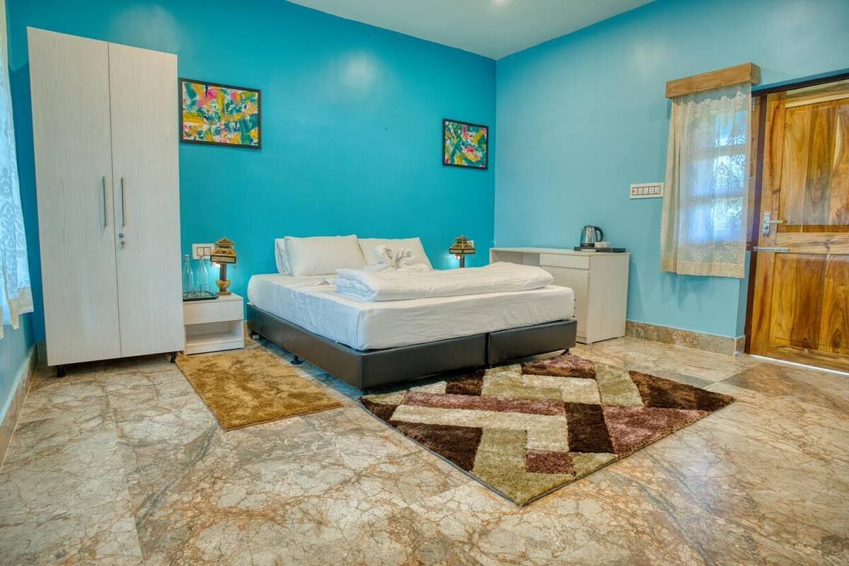 A bedroom with a bed, nightstands, a wardrobe, and artwork on the walls.