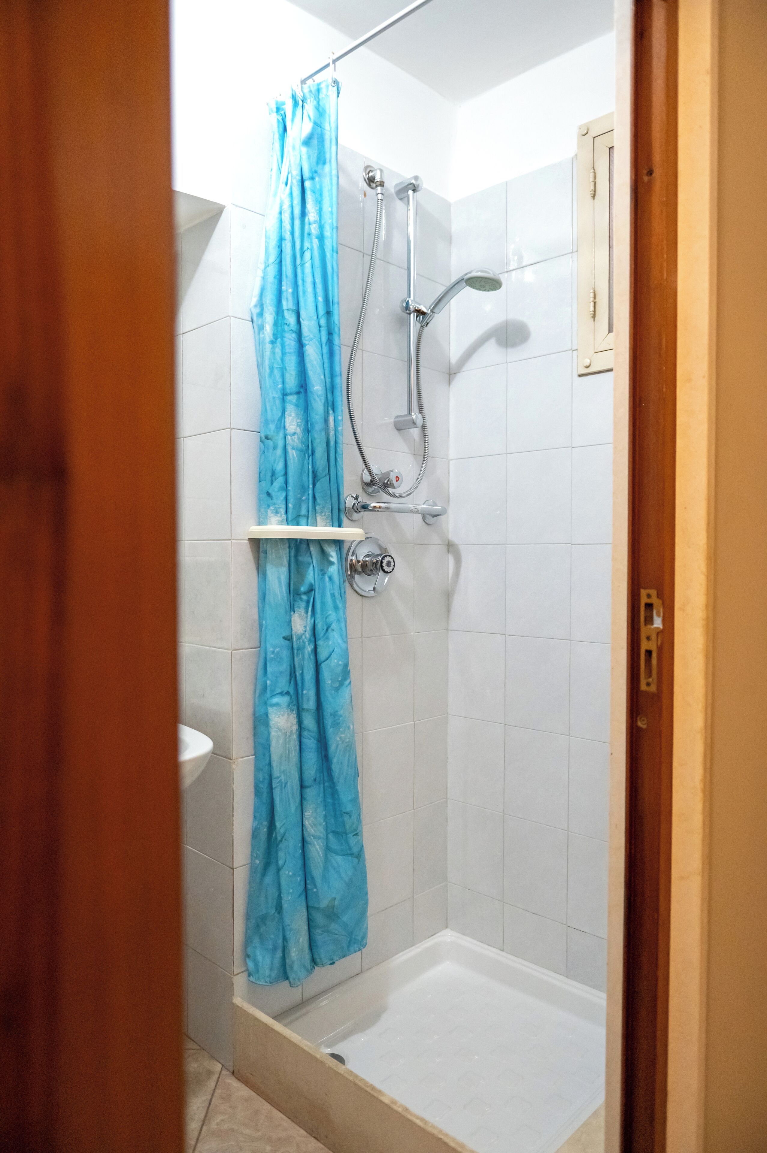 Een douche met een blauw gordijn, een handdouche en een muurbevestigde kraan.