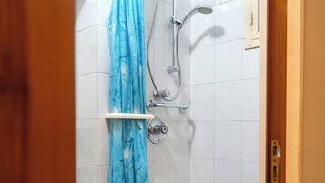 Een douche met een blauw gordijn, een handdouche en een muurbevestigde kraan.
