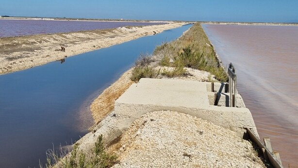 Una plataforma de formigó amb vistes a una calma extensió d'aigua sota un cel serè.