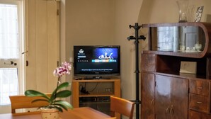 Un saló amb televisió, un armari de fusta i una taula de menjador amb cadires.