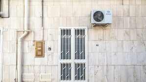 Fachada d'edifici amb una porta blanca, unitat de aire condicionat i reixes de ventilació.