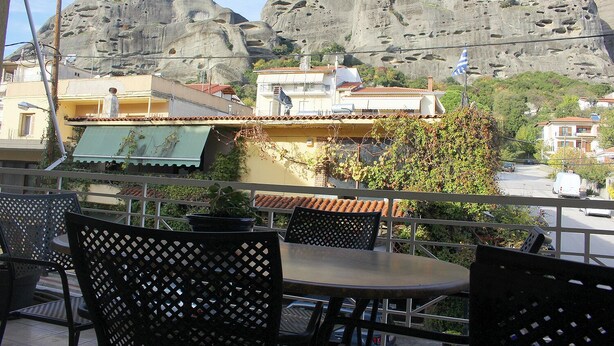A terrace with outdoor seating, overlooking a rocky landscape and residential buildings. - Alkinoos Apt -Inspiring Living in Meteora -3BD (Kalampaka)