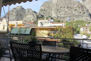 A terrace with outdoor seating, overlooking a rocky landscape and residential buildings. - Alkinoos Apt -Inspiring Living in Meteora -3BD (Kalampaka)