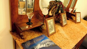 A wooden vanity with a mirror, framed photographs, a candle, and a book on a marble countertop. - Alkinoos Apt -Inspiring Living in Meteora -3BD (Kalampaka)