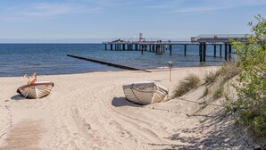 A beach with a pier, two boats, and a wooden walkway.