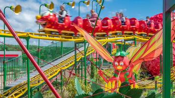 A roller coaster with red cars and a large dragon figure.