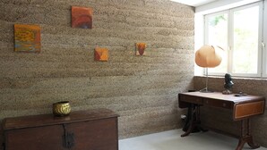 Ein Zimmer mit einer strukturierten Steinwand, einem Holztisch mit Lampe und einer alten Kommode.