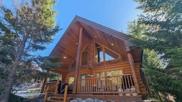 Une cabane en rondins avec un porche en bois et des fondations en pierre.