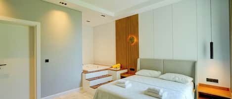 Una habitación de hotel moderna con una cama grande, una bañera empotrada y un panel de pared de madera.