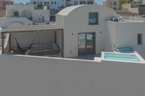 A modern building with a covered seating area and a pool. - Anemos Imerovigli Suites (Santorini)