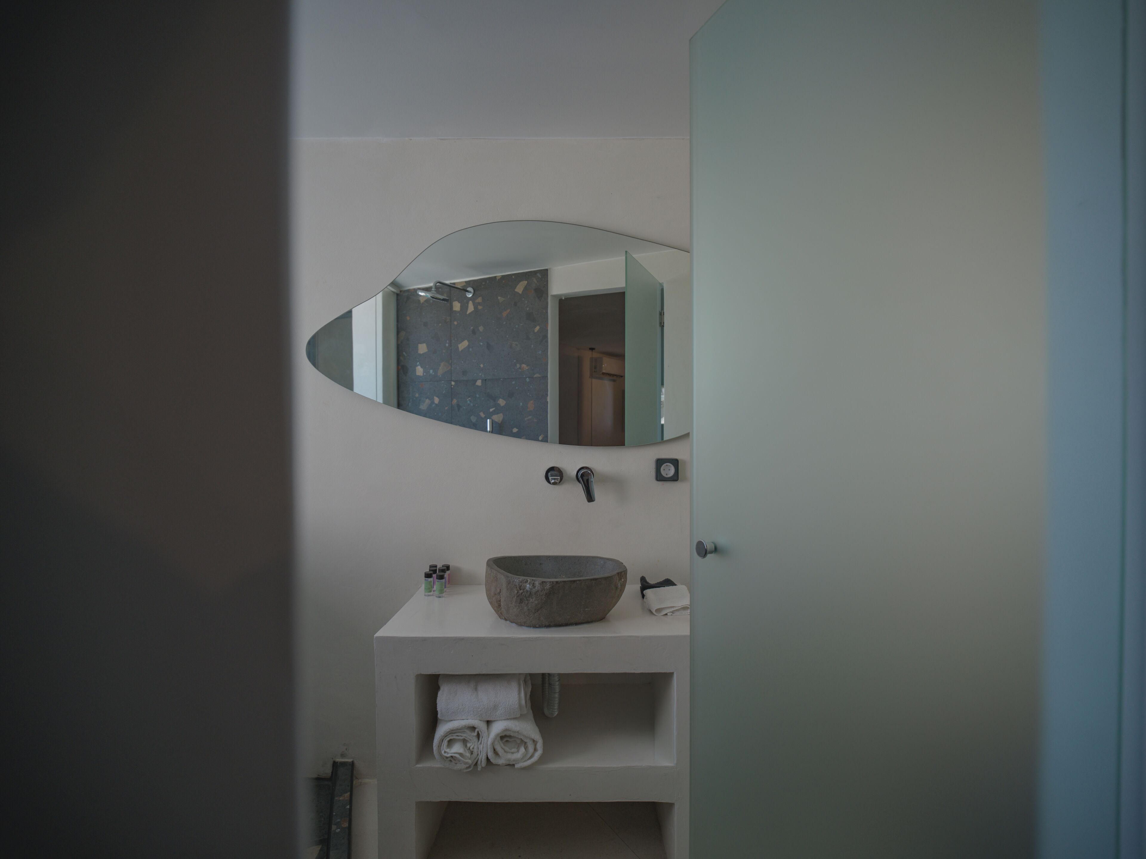 Een badkamer met een wit wastafelmeubel, een rond wastafel, een spiegel en een handdoekrek.